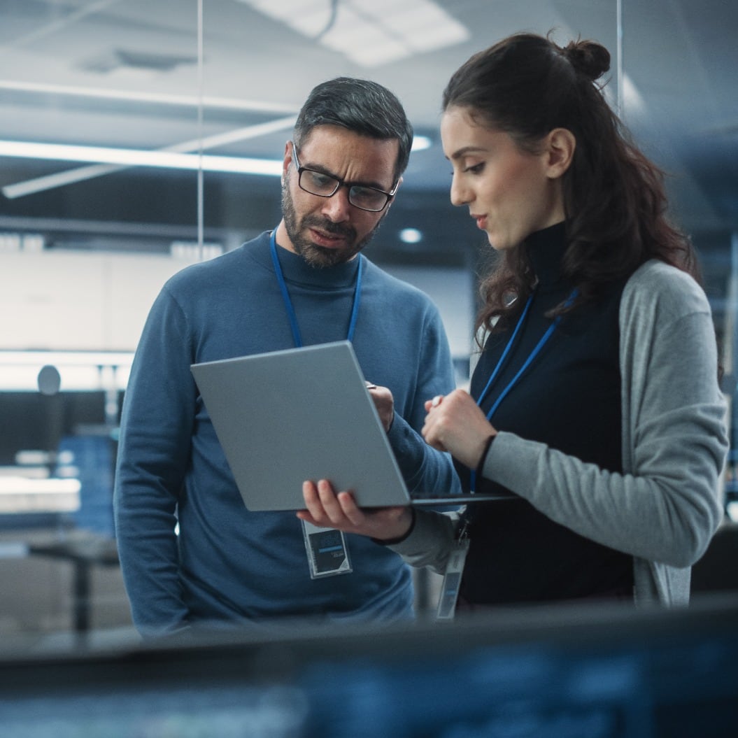 Portrait of Two Female and Male Engineers Using Laptop Computer to Analyze and Discuss How to Proceed with the Artificial Intelligence Software. Casually Chatting in High Tech Research Office